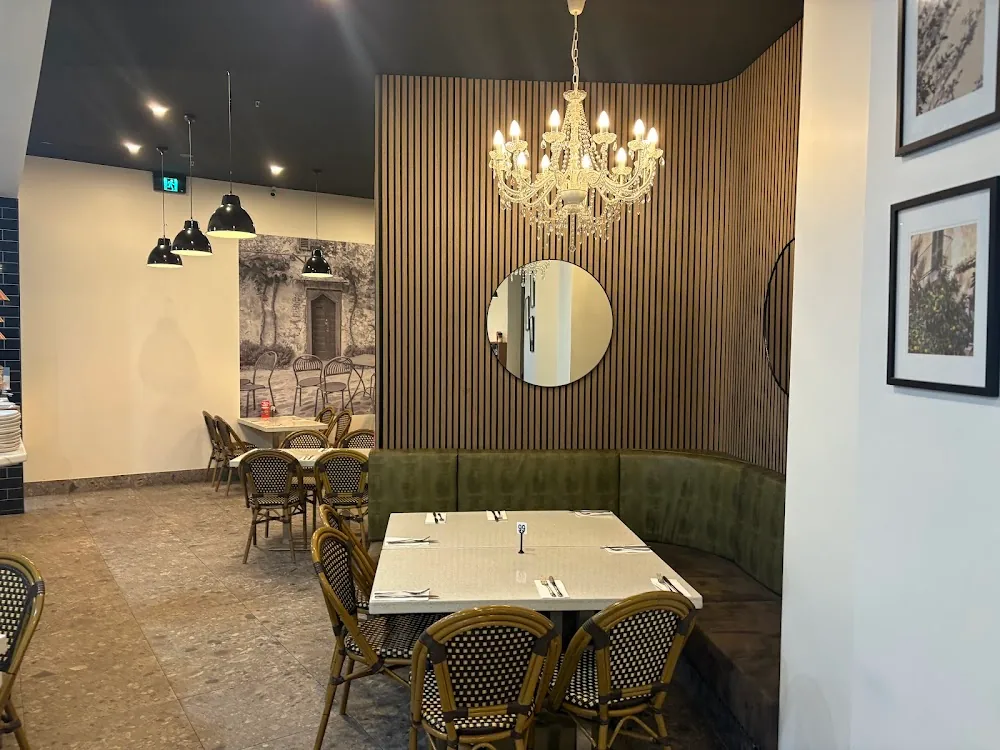 Garibaldi private seating with olive green banquette and woven bistro chairs